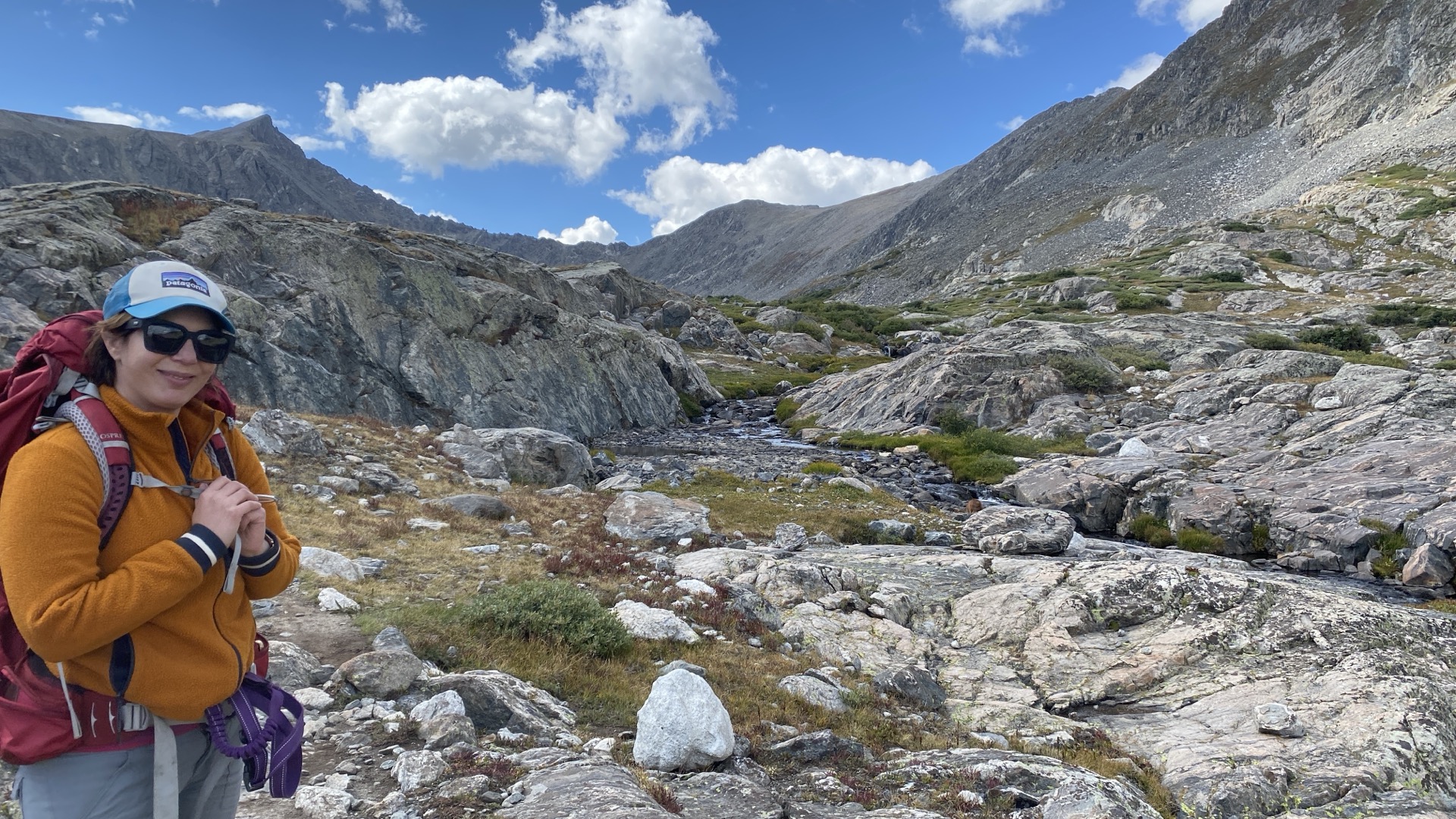 A backpacker in a granite alpine basin beside a stream
