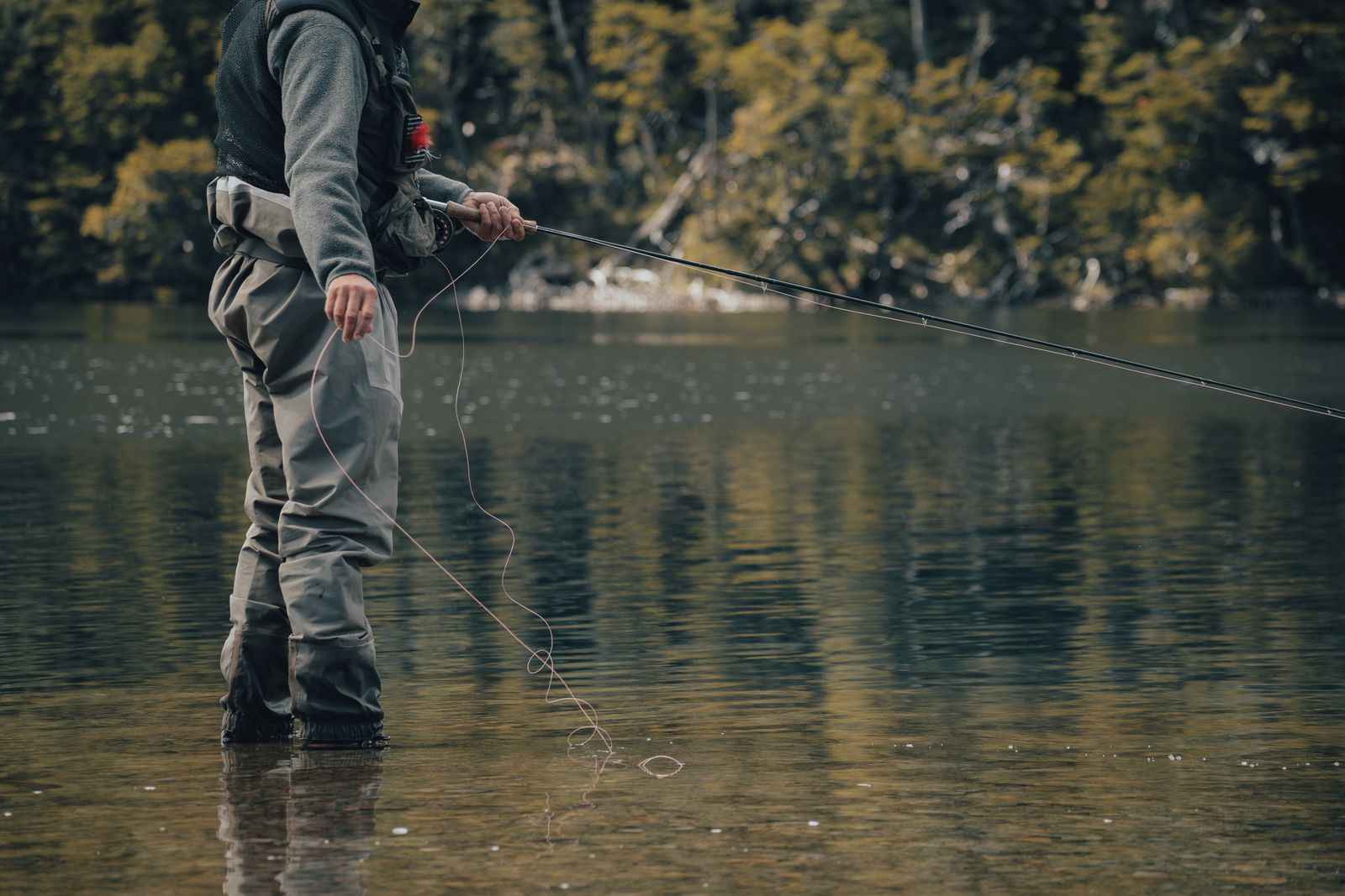 An angler casting a fly line on a mountain river